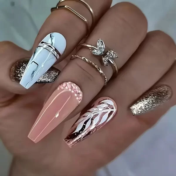 Long coffin-shaped press-on nails with leaf design in gold, white, and pink.